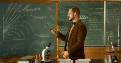 A fictional character, Dr. Rolf pointing to a graph on a chalkboard.