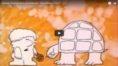 A cartoon image of a man offering a cartoon image of a turtle a tootsie pop sucker.